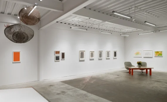 Gallery space with white walls, hanging sculpture and artwork on walls.