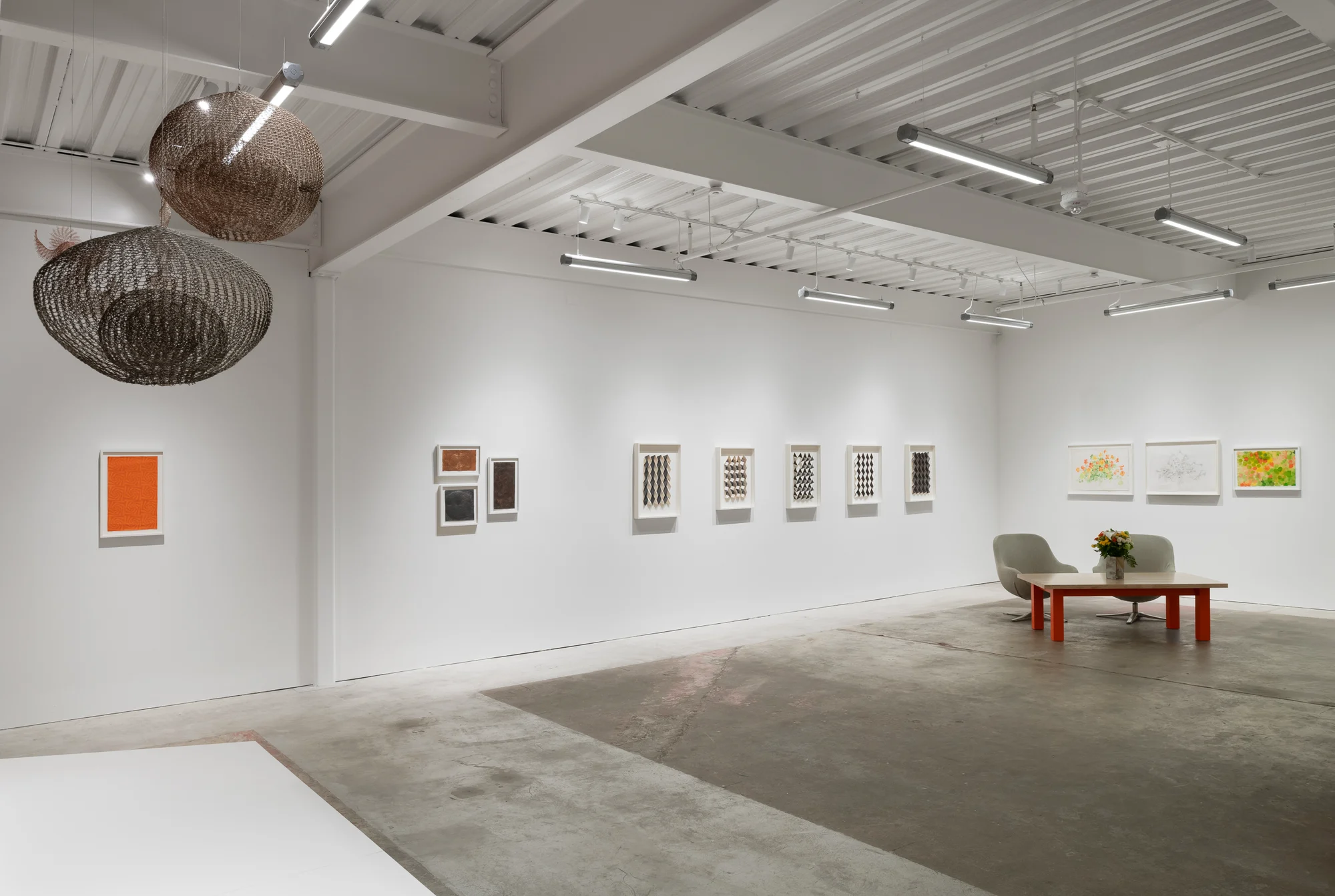Gallery space with white walls, hanging sculpture and artwork on walls.